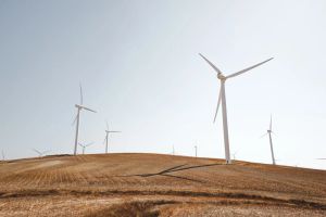 Wind turbines standing in a grass field in Spain.